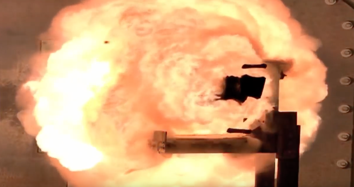 Railgun projectile bursting through a metal plate in a Navy test system.